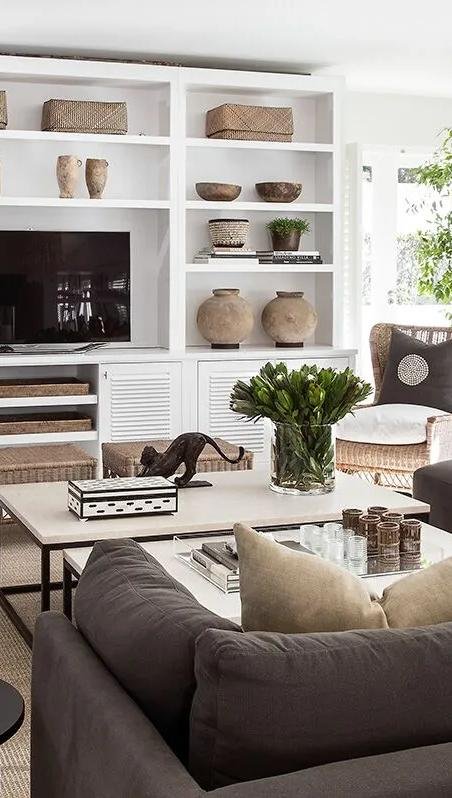 A contemporary living room with woven baskets, ceramic vessels and collected objects on white shelving